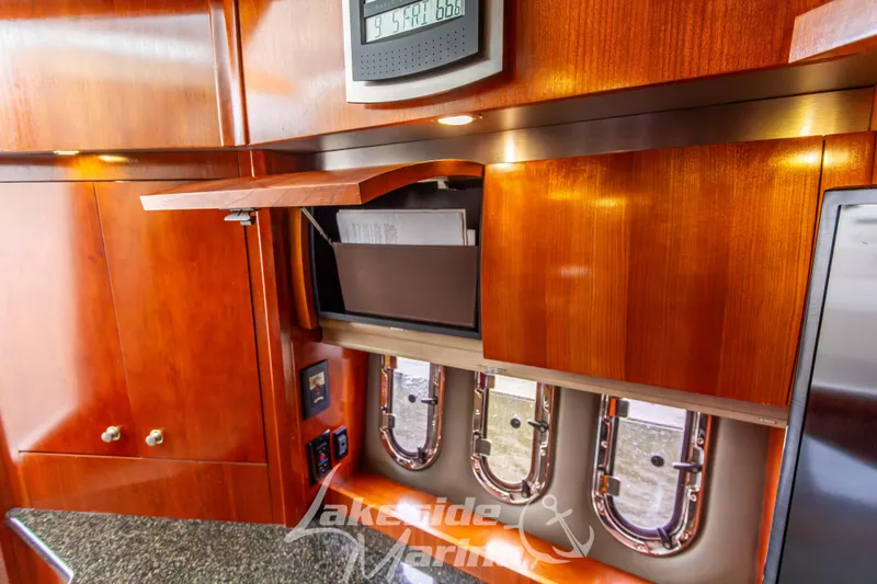 Slide: The Image of 2006 Cruisers Yachts 420 Express interior with wooden cabinetry and porthole windows. - 76
