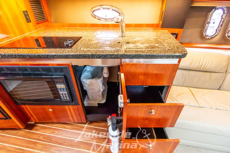 Slide: The Image of 2006 Cruisers Yachts 420 Express interior kitchen with granite countertop and wooden cabinetry. - 91