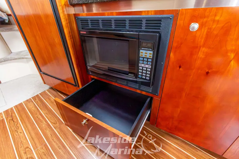 Slide: The Image of 2006 Cruisers Yachts 420 Express interior with microwave and wooden cabinetry. - 92
