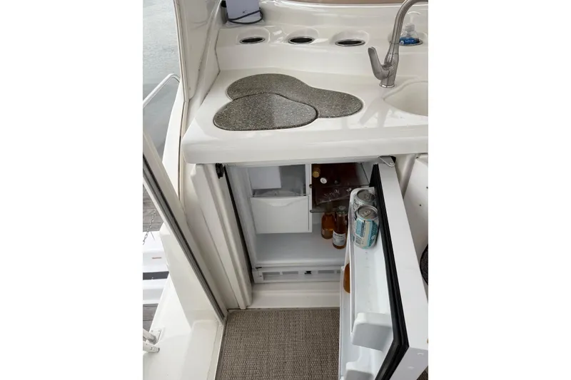 Slide: The Image of 2001 Cruisers 4450 ACMY yacht kitchenette with open mini fridge and sink. - 11