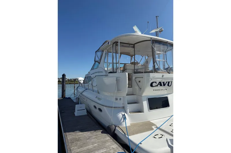 Slide: The Image of 2001 Cruisers 4450 ACMY yacht docked, featuring spacious deck and clear skies. - 3