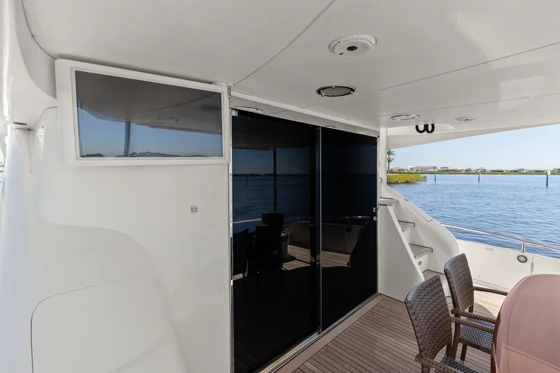 Slide: The Image of Luxury Lazzara yacht deck with wicker chairs, glass doors, and scenic water view. - 22