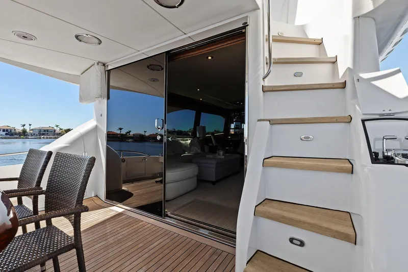 Slide: The Image of Luxurious Lazzara yacht deck with wicker chairs, stairs, and glass doors overlooking water. - 23