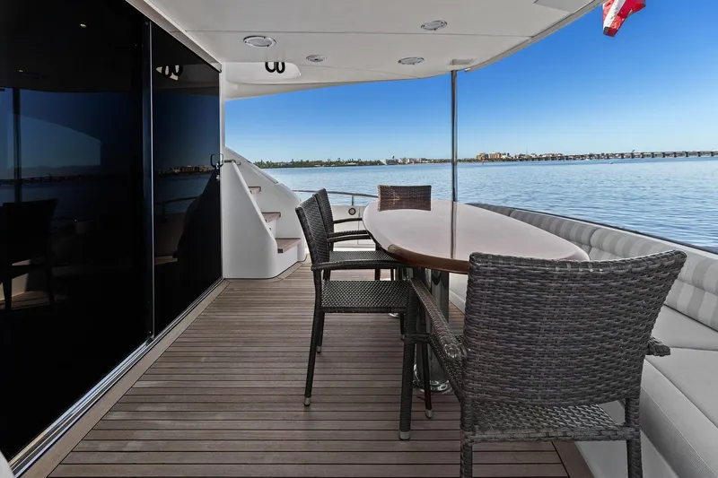 Slide: The Image of Luxury Lazzara yacht deck with dining area overlooking serene water and distant cityscape. - 25