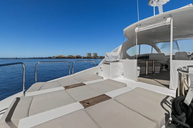 Slide: The Image of Luxury Lazzara yacht deck with sun loungers, overlooking calm blue waters and distant cityscape. - 28