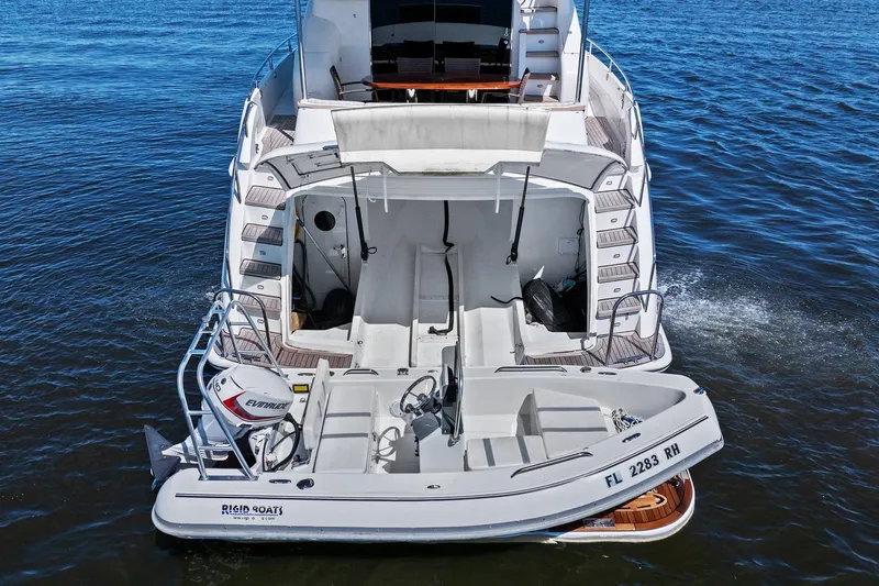 Slide: The Image of Lazzara yacht with tender boat on water, featuring Evinrude motor and Rigid Boats branding. - 5