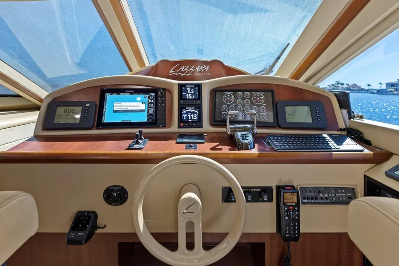 Slide: The Image of Lazzara yacht helm with navigation screens, controls, and steering wheel, overlooking a sunny seascape. - 64