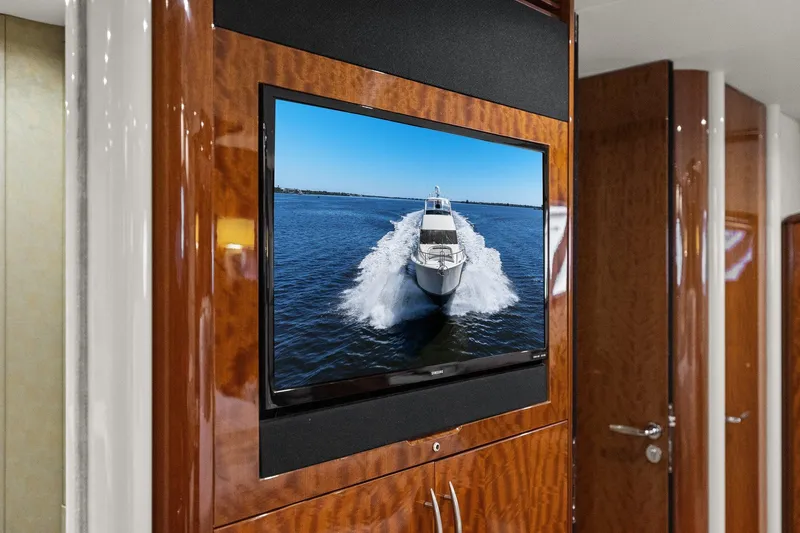 Slide: The Image of Flat-screen TV displaying a Lazzara yacht cruising on water, mounted on a wooden wall. - 71