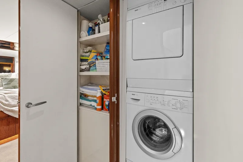 Slide: The Image of Laundry area on a Lazzara yacht with stacked washer and dryer, and storage shelves. - 91