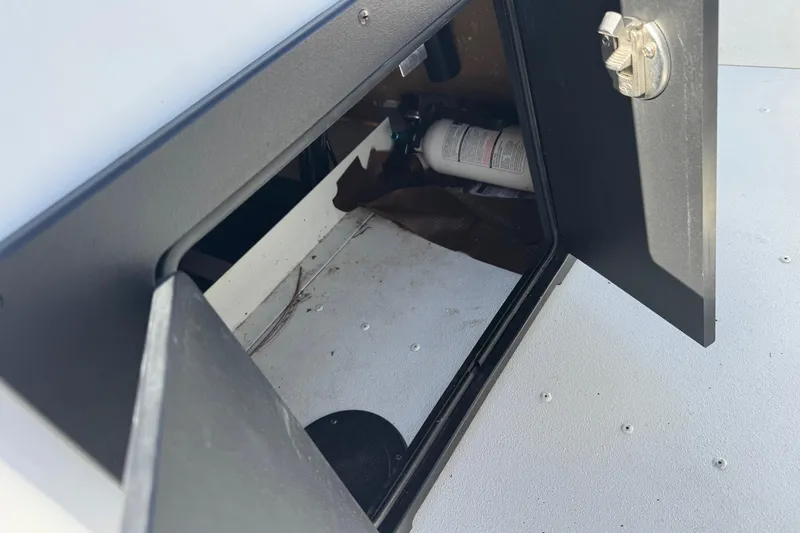 Slide: The Image of Open storage compartment on 2023 G3 Bay 17 boat, revealing interior and fire extinguisher. - 17