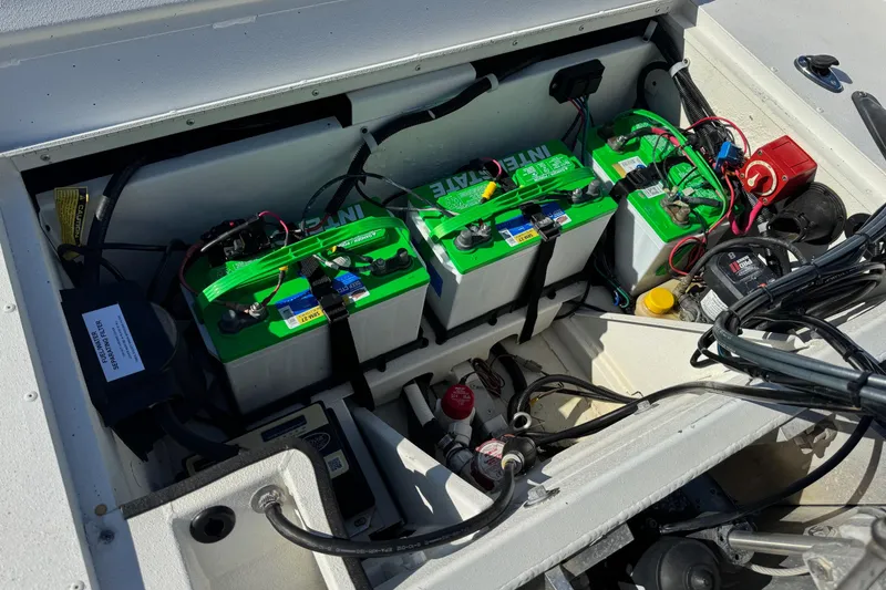 Slide: The Image of Battery compartment of 2023 G3 Bay 17 boat with three green batteries and wiring. - 19