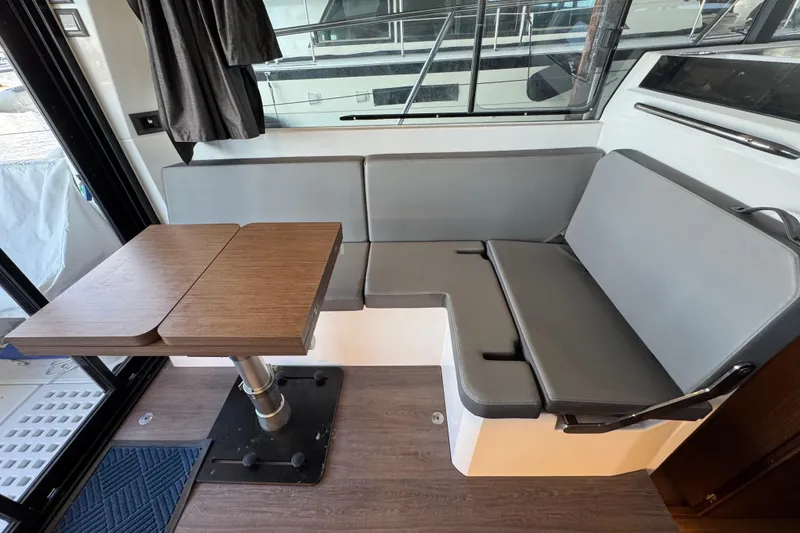 Slide: The Image of Interior of 2025 Beneteau Antares 11 Fly with gray seating and wooden table. - 16