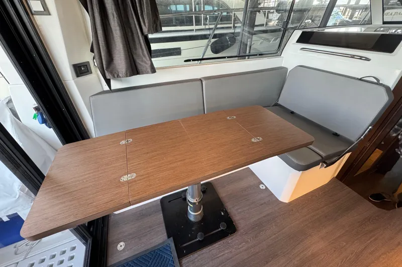 Slide: The Image of Interior of 2025 Beneteau Antares 11 Fly with wooden table and gray seating. - 17