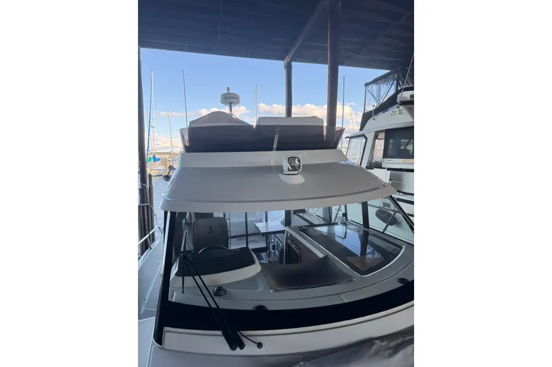 Slide: The Image of 2025 Beneteau Antares 11 Fly yacht docked under a covered marina. - 48