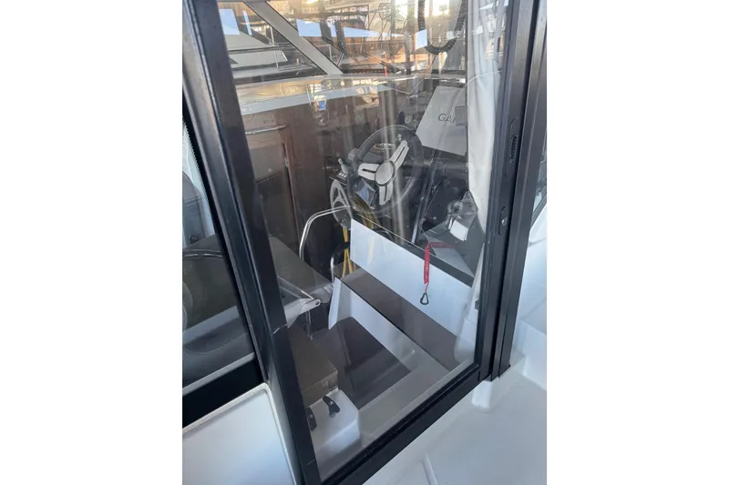 Slide: The Image of 2025 Beneteau Antares 11 Fly cockpit view through glass door, showcasing steering wheel. - 51