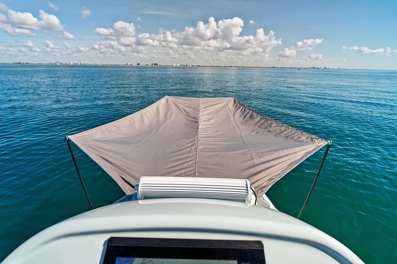 Slide: The Image of 2023 Barker Boatworks 26 Open on calm ocean with canopy, clear sky, and distant cityscape. - 24