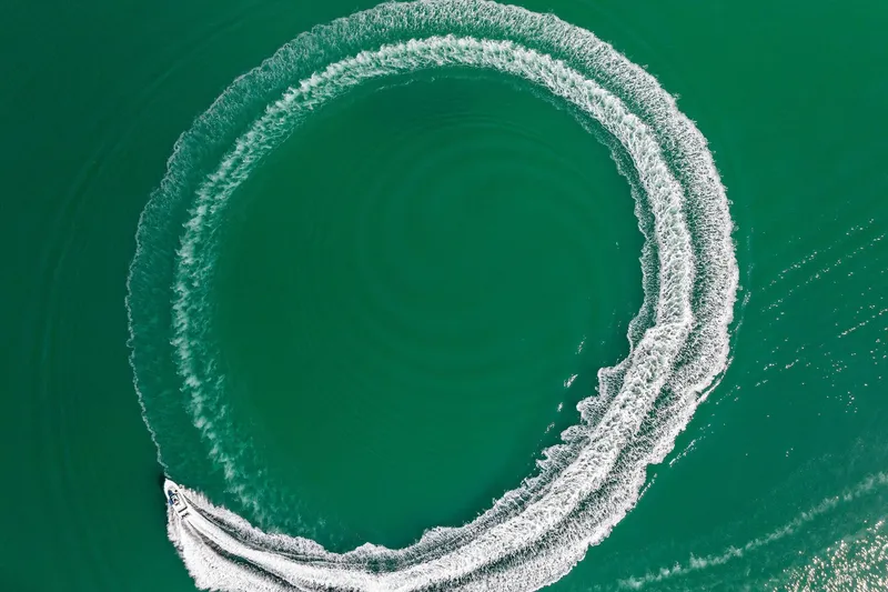 Slide: The Image of Aerial view of 2023 Barker Boatworks 26 Open creating circular wake in turquoise water. - 48