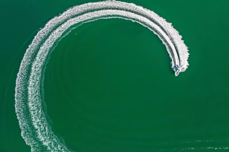 Slide: The Image of Aerial view of 2023 Barker Boatworks 26 Open creating circular wake on green water. - 50