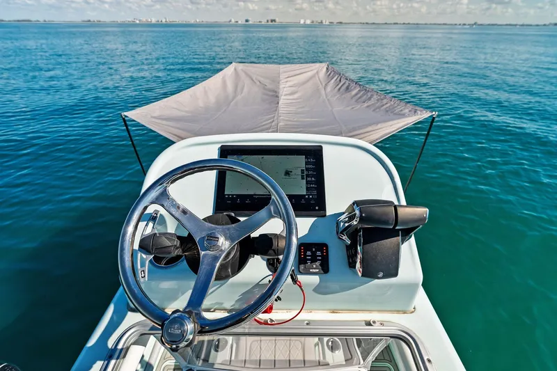 Slide: The Image of 2023 Barker Boatworks 26 Open helm with steering wheel and navigation display on calm water. - 28