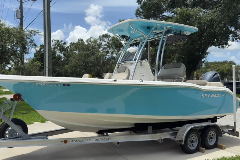 Slide: The Image of 2023 Key West 219 FS boat on trailer, light blue hull, parked outdoors. - 0