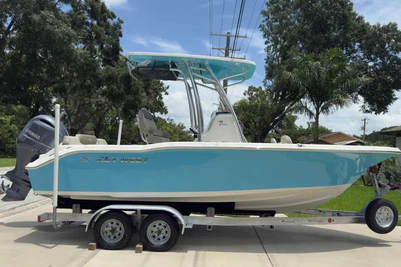 Slide: The Image of 2023 Key West 219 FS boat on trailer, light blue hull, parked outdoors. - 1