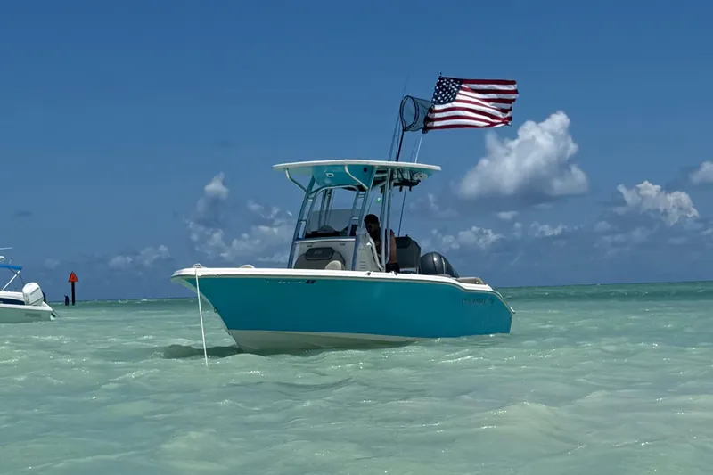 Slide: The Image of 2023 Key West 219 FS boat with American flag on turquoise water under blue sky. - 2
