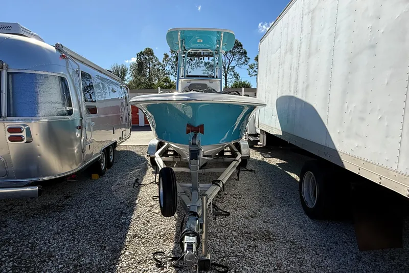 Slide: The Image of 2023 Key West 219 FS boat on trailer between vehicles, parked outdoors. - 41