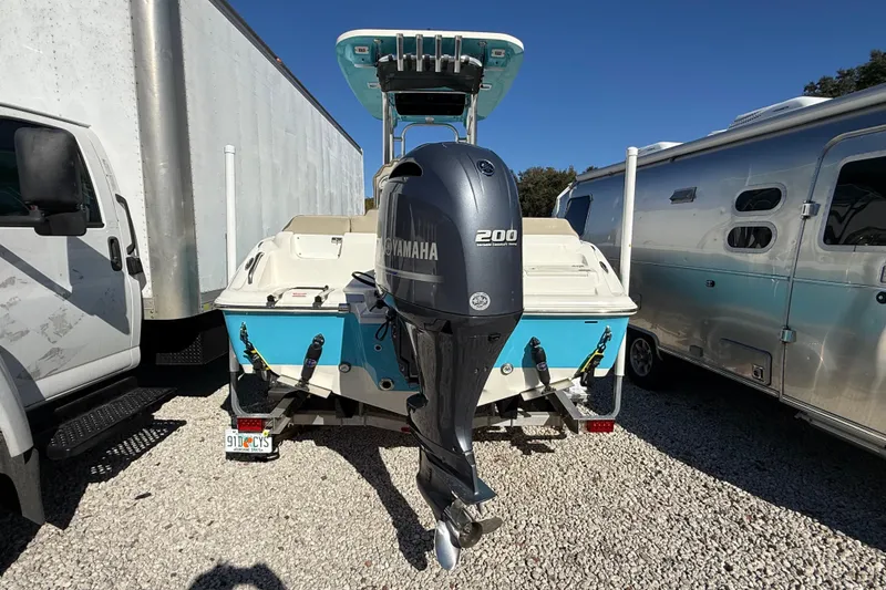 Slide: The Image of 2023 Key West 219 FS boat with Yamaha 200 engine, parked between vehicles. - 52