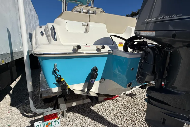 Slide: The Image of 2023 Key West 219 FS boat with blue and white hull, parked on gravel. - 55