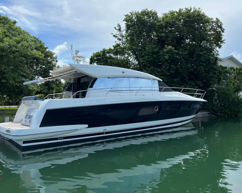Slide: The Image of 2013 Prestige 500 S yacht docked on calm water, surrounded by lush greenery. - 1