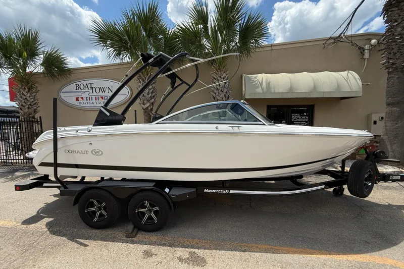 The Image of 2024 Cobalt 220S boat on trailer at Boat Town dealership, sunny day. - 0