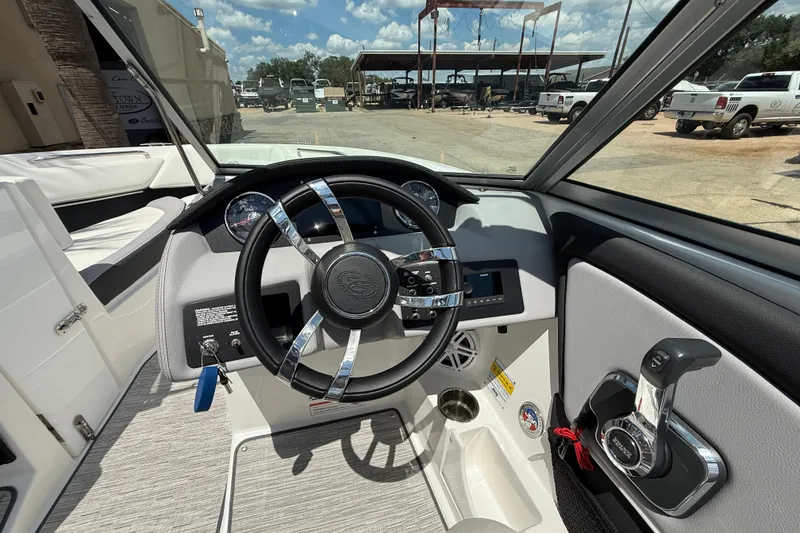 Slide: The Image of 2024 Cobalt 220S boat cockpit with steering wheel and control panel, outdoor setting. - 11