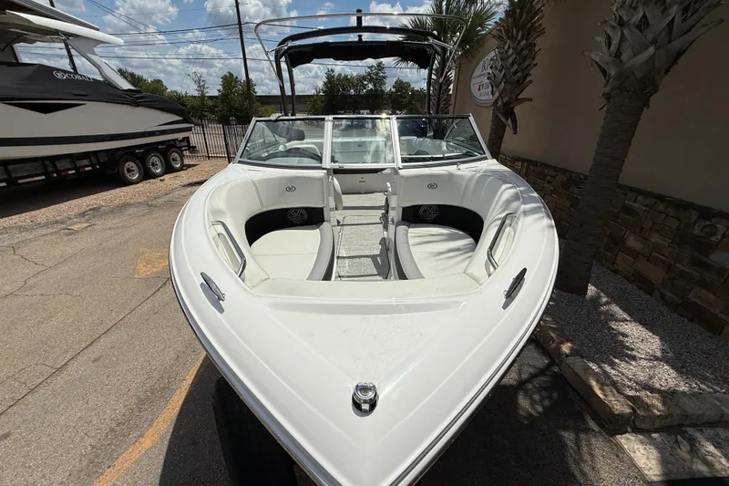Slide: The Image of 2024 Cobalt 220S boat with sleek white design, docked outdoors under a sunny sky. - 2