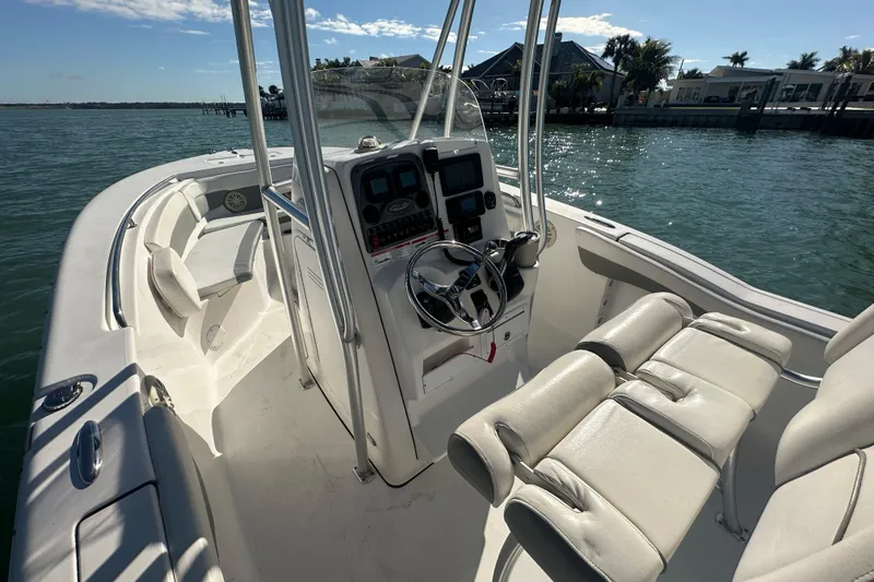 Slide: The Image of 2018 Tidewater 232 LXF boat interior with steering console and seating, docked by the water. - 10