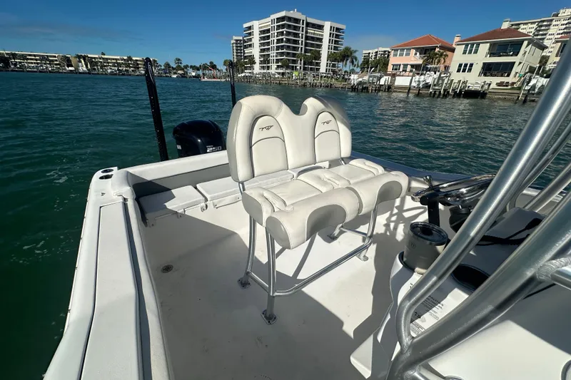 Slide: The Image of 2018 Tidewater 232 LXF boat interior with seating, docked near waterfront buildings. - 11