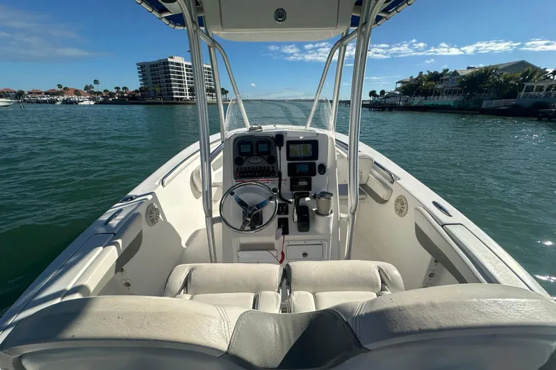 Slide: The Image of 2018 Tidewater 232 LXF boat on water, featuring helm and seating, with coastal view. - 14