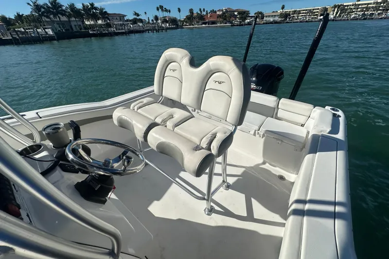 Slide: The Image of 2018 Tidewater 232 LXF boat interior with helm and seating, docked on calm water. - 9