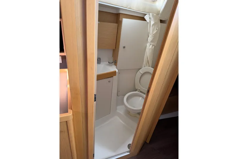 Slide: The Image of 2014 Beneteau 38 yacht bathroom with toilet, sink, and wooden cabinetry. - 6