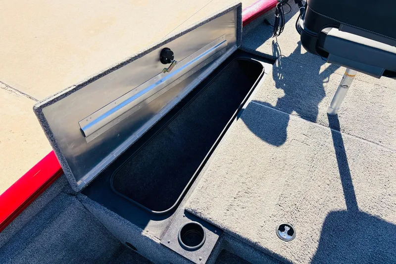 Slide: The Image of 2024 Tracker Pro Team 175 TXW boat storage compartment with open lid, carpeted interior. - 16