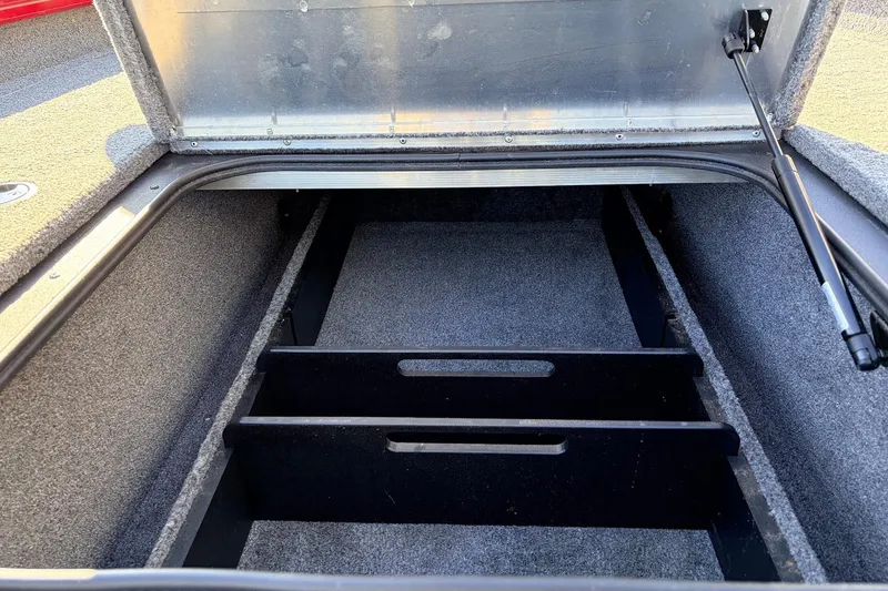 Slide: The Image of 2024 Tracker Pro Team 175 TXW boat storage compartment, open lid, carpeted interior. - 20