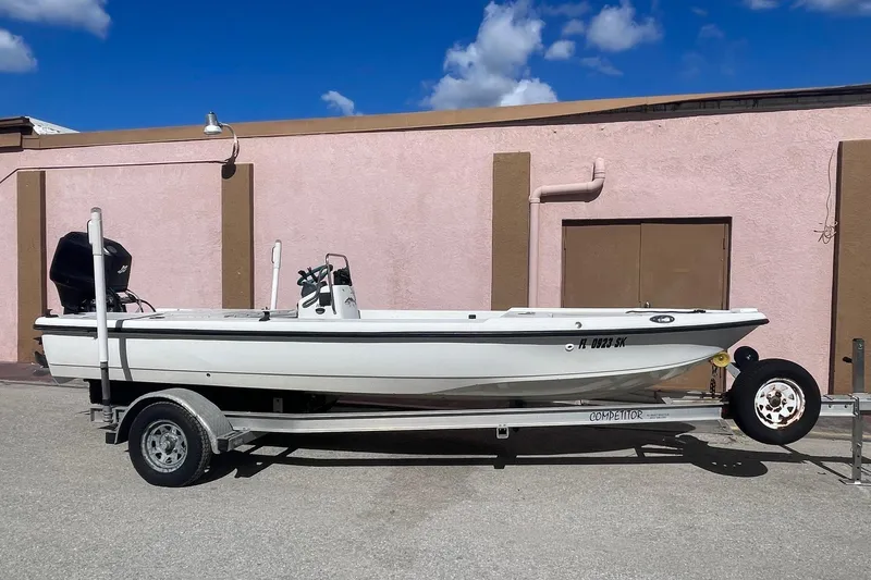The Image of 2002 Action Craft 1802 boat on trailer, parked against a pink wall under blue sky. - 1