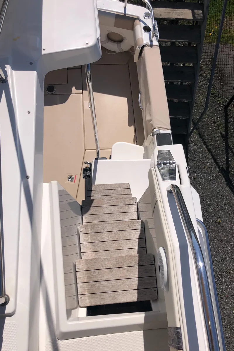 Slide: The Image of 2016 Cutwater 30 Command Bridge boat deck with wooden steps and seating area. - 13