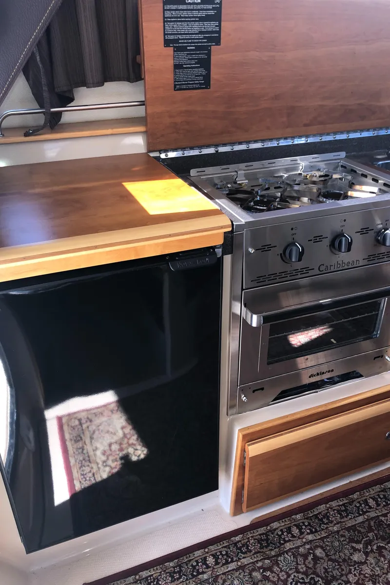 Slide: The Image of 2016 Cutwater 30 Command Bridge kitchen with stove, oven, and compact refrigerator. - 30