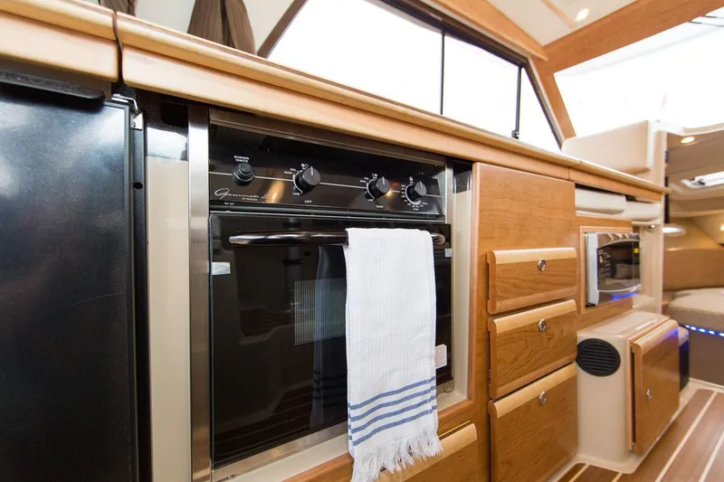Slide: The Image of Interior of 2016 Cutwater 30 Command Bridge, featuring a modern kitchen with wooden cabinetry. - 31