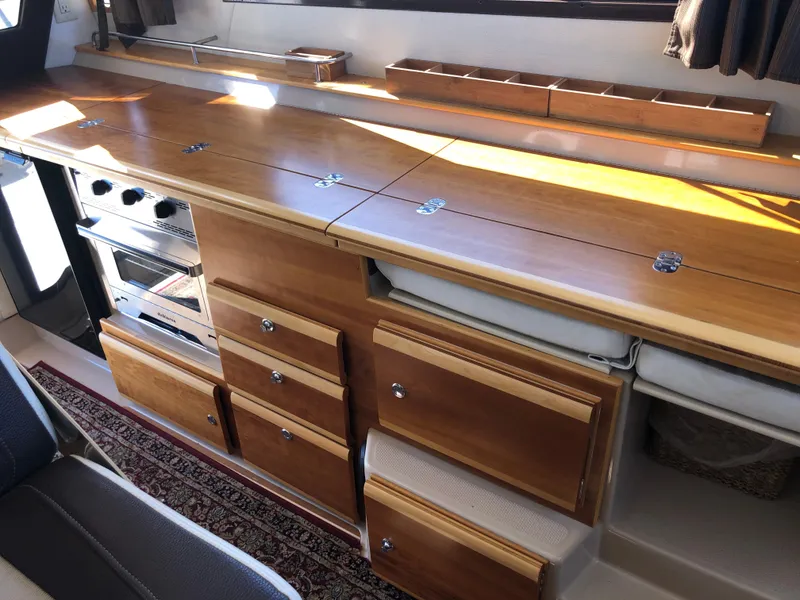 Slide: The Image of 2016 Cutwater 30 Command Bridge interior kitchen with wooden cabinets and stove. - 32