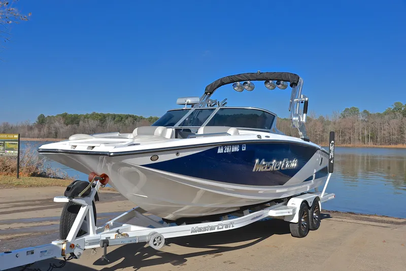 Slide: The Image of 2013 MasterCraft X-35 boat on trailer by a lake under clear blue sky. - 11