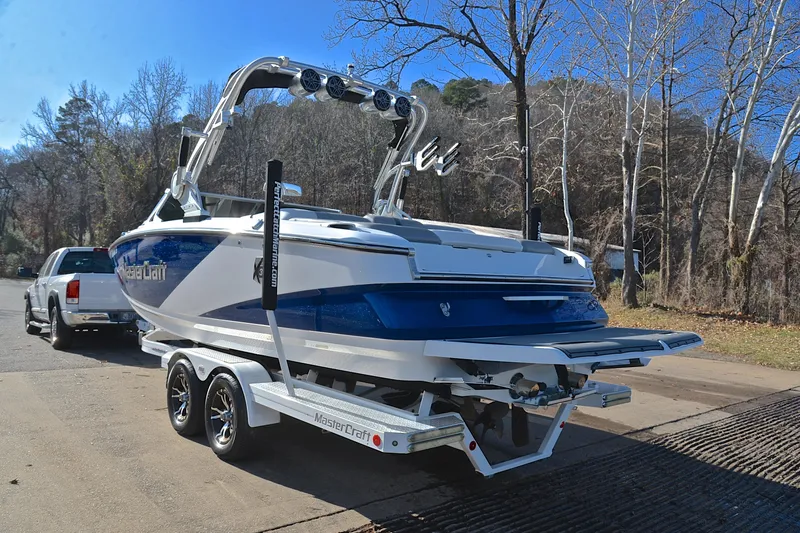 Slide: The Image of 2013 MasterCraft X-35 boat on trailer, parked near wooded area. - 13