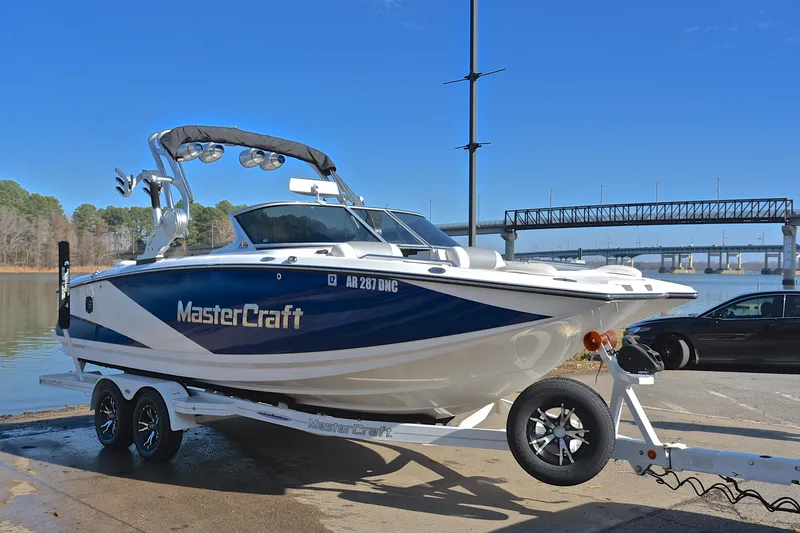 Slide: The Image of 2013 MasterCraft X-35 boat on trailer by a lake, under clear blue sky. - 17