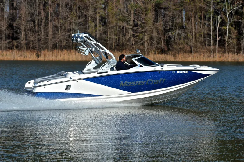 Slide: The Image of 2013 MasterCraft X-35 boat cruising on a lake with wooded shoreline. - 3