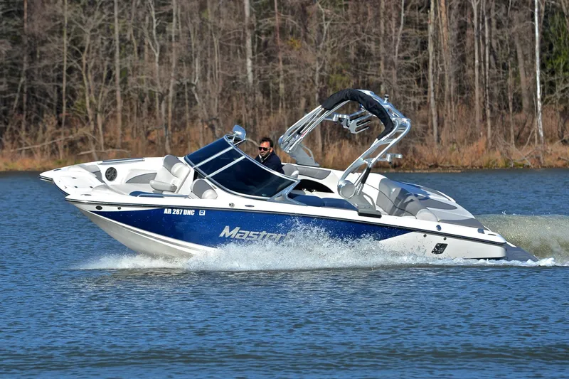 Slide: The Image of 2013 MasterCraft X-35 boat cruising on a lake with wooded shoreline. - 7